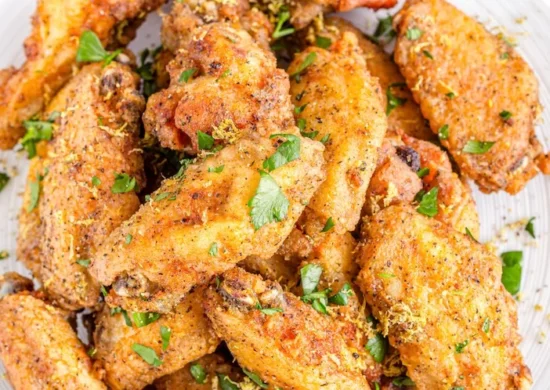 Crispy golden chicken wings on a white plate, garnished with parsley for flavor and color.