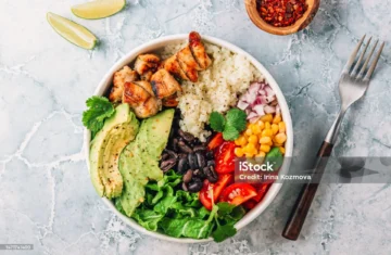 Grilled chicken bowl with rice, fresh veggies, avocado, and lime for a delicious meal.