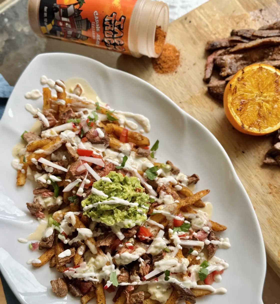 Loaded fries topped with shredded beef, creamy sauce, guacamole, and fresh garnishes - ideal for foodservice establishments and commercial kitchens.